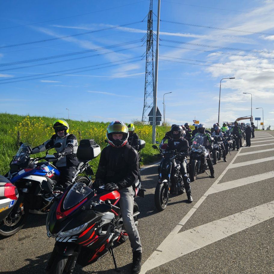 Dagtour 26 april 2026 Groep motorrijders op een weg, omringd door groene velden en blauwe lucht.